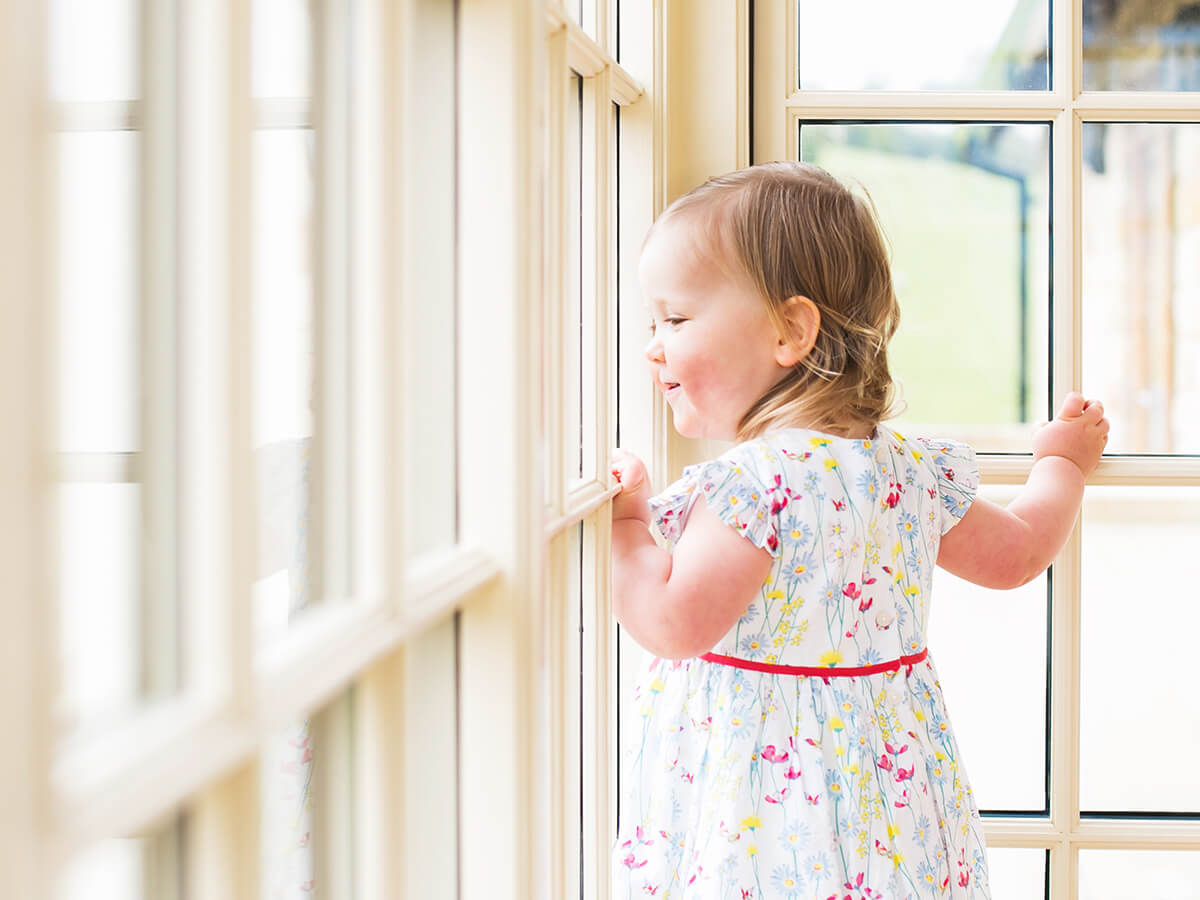 Colour photo of a Little girl standing on a window sill with a lovely angle