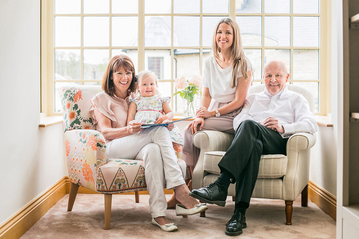 Colour photograph of two year old girl with Mum and Grandparents in a beautiful house