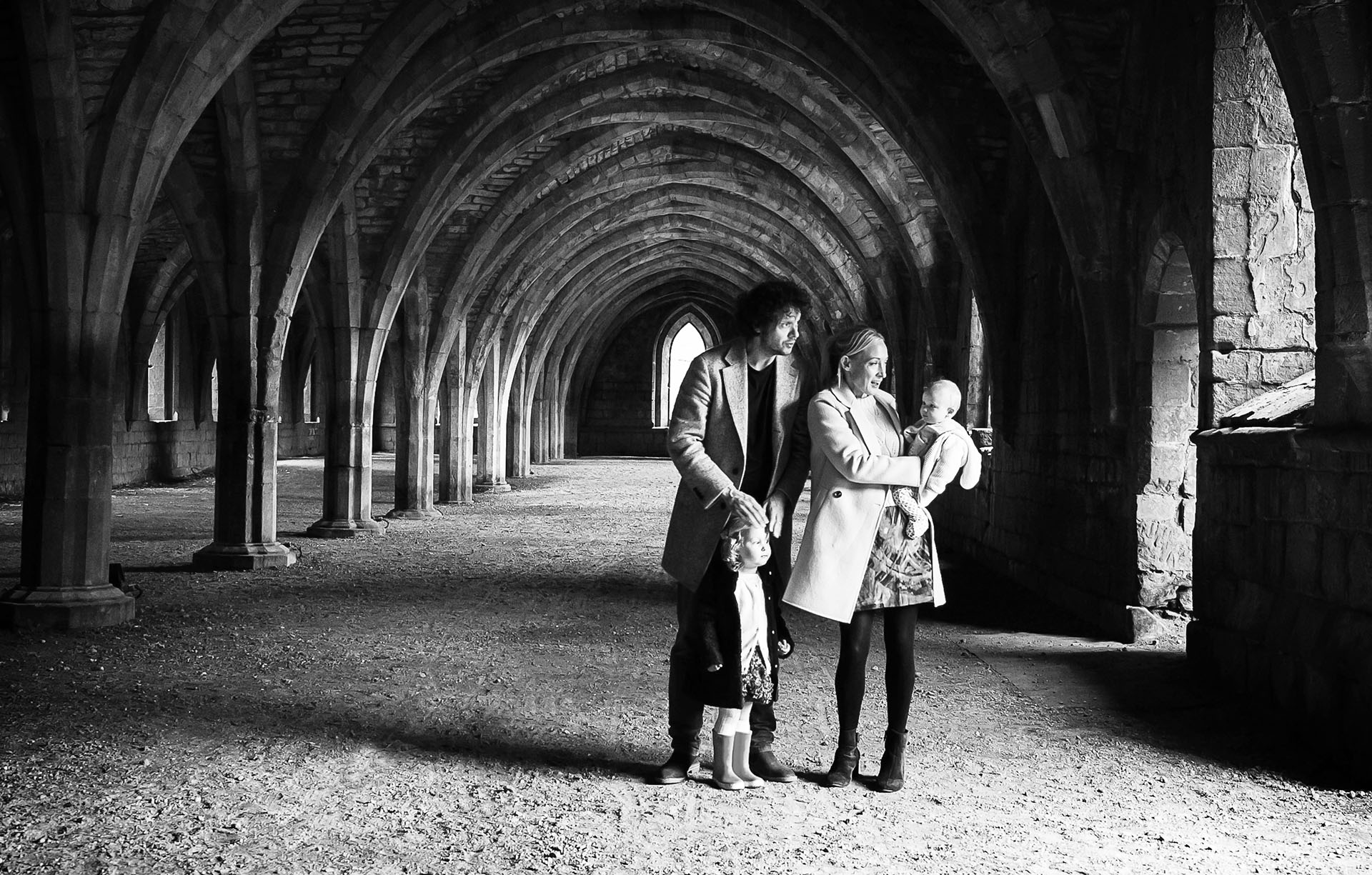 B&W photo of a family in the arches of Fountains Abbey