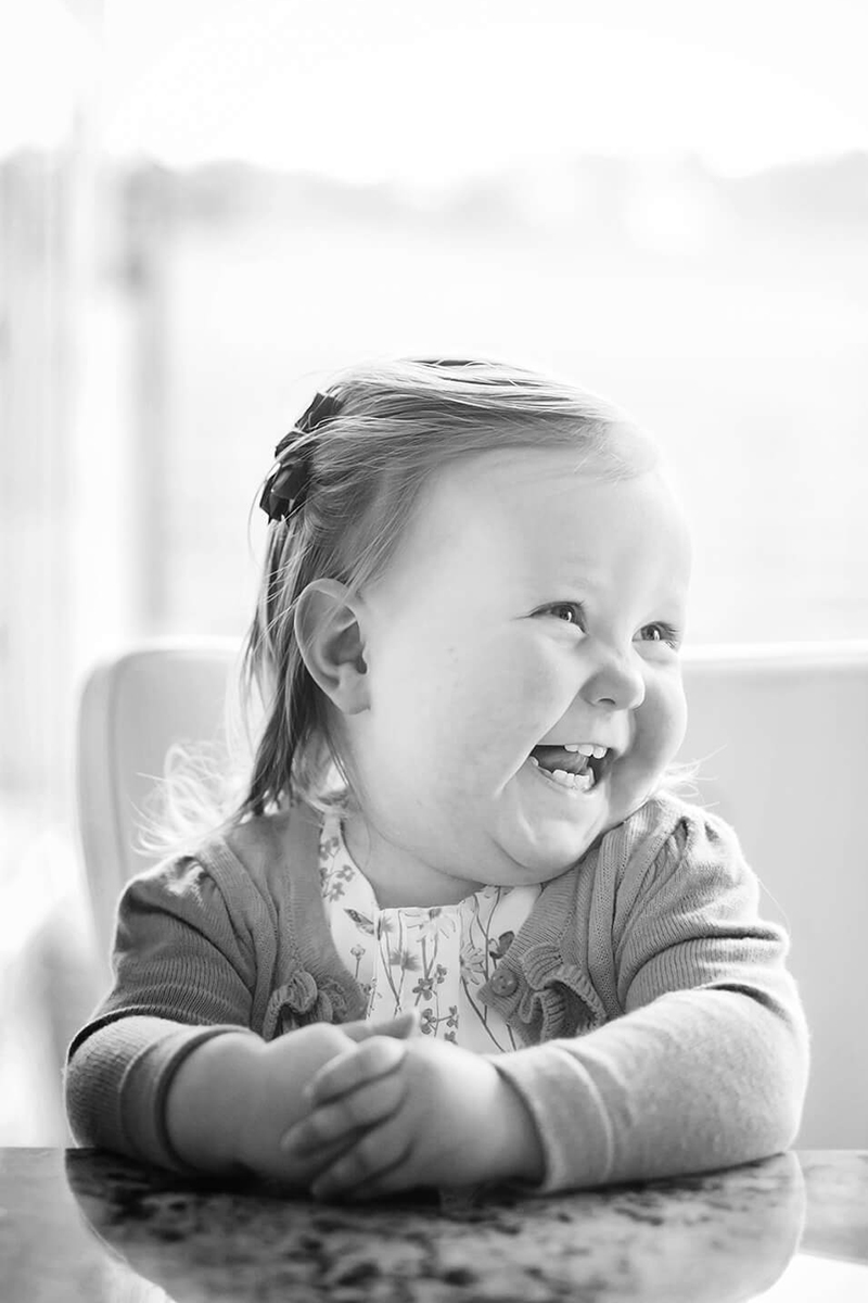 B&W photo of a giggling 2 year old in a kitchen in Ilkley