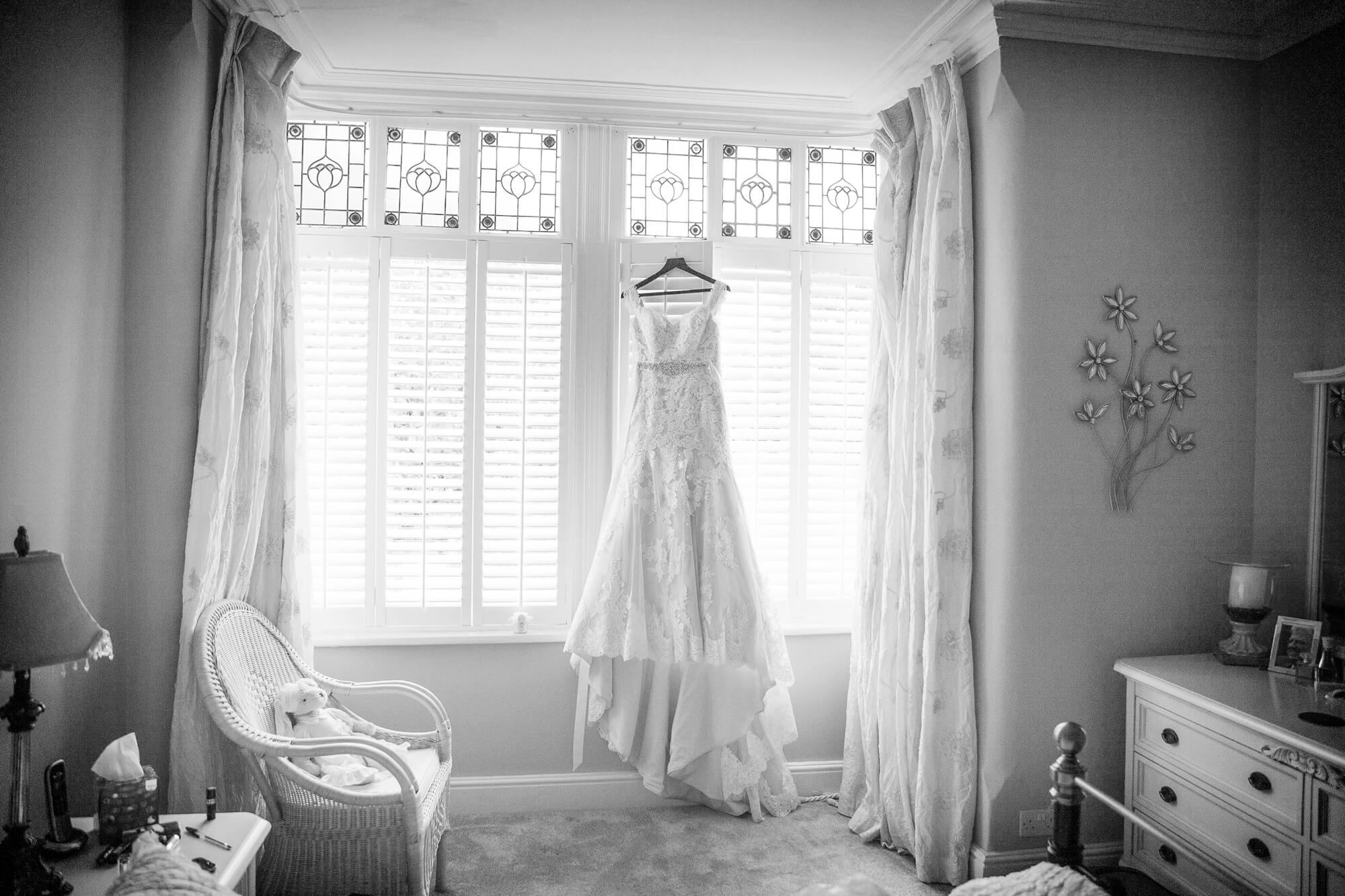 black & white image of wedding dress hanging in feature window