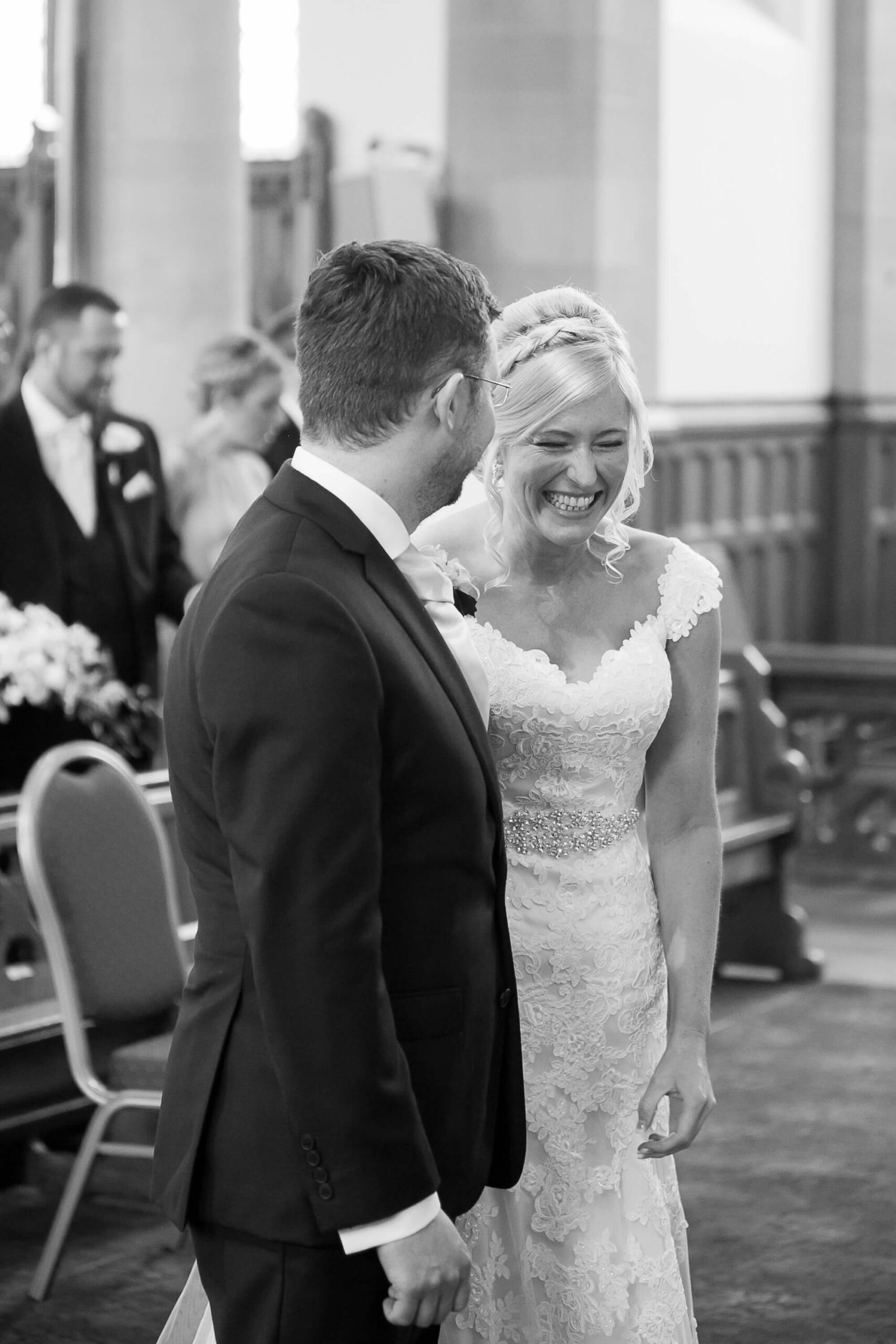 Black & white photos of bride laughing at the altar with groom