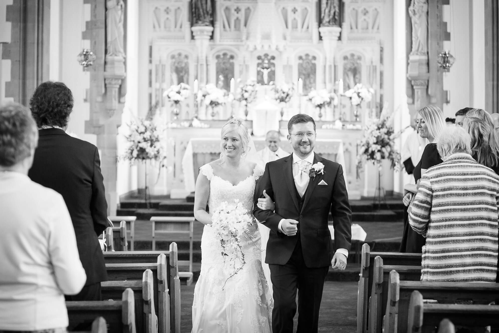 Lovely black & white photo of bride and groom walking down the isle after getting married