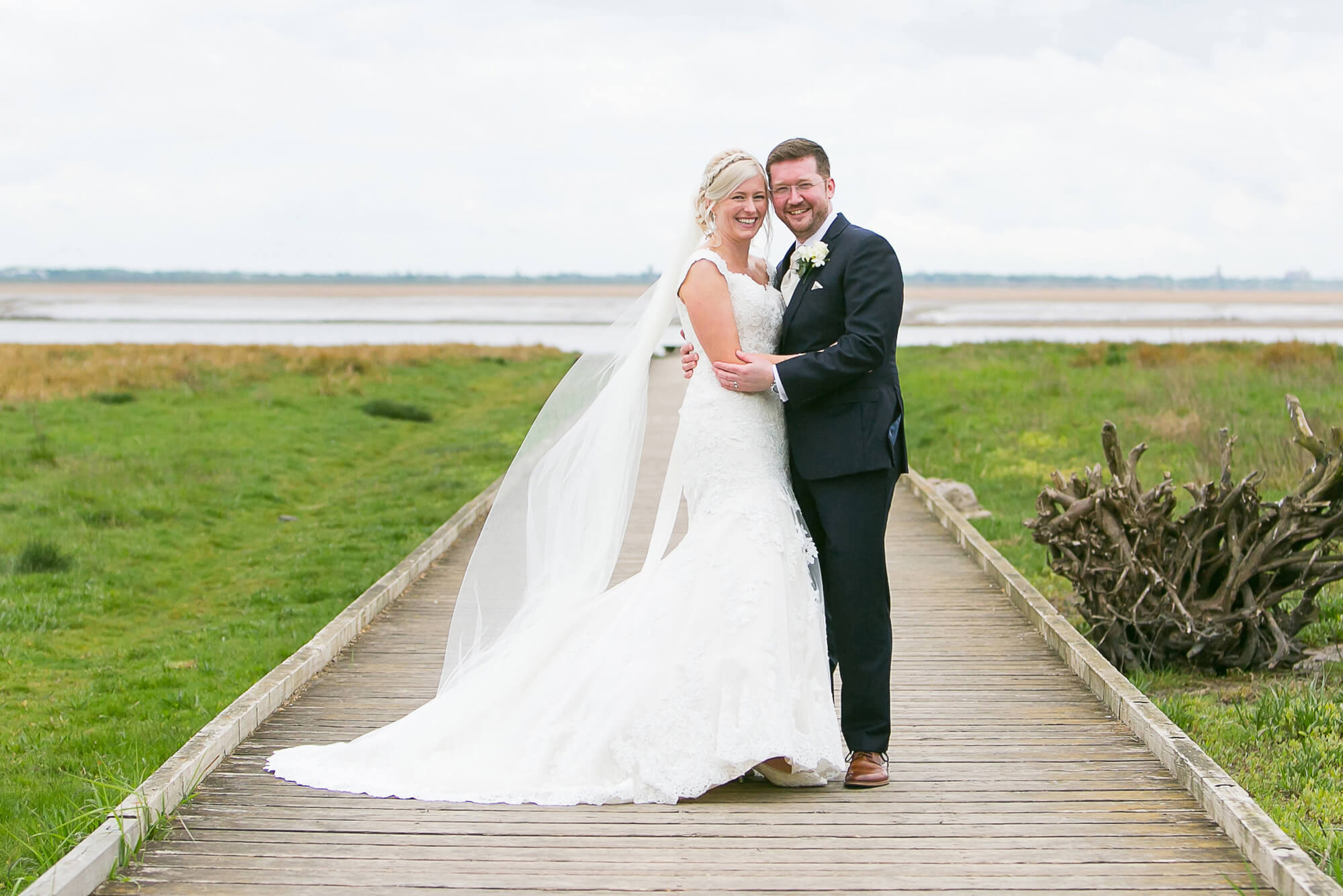 colour photo of bride and groom on walkway to the beach